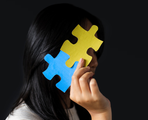 Is Pathological Demand Avoidance : Pervasive Need for Autonomy (PDA) Related to Autism?, image of girl hiding face with jig saw puzzle.